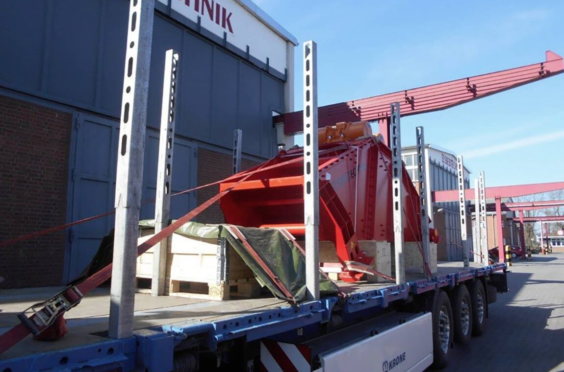 Linear vibrating screen HR 14-40-I FR. The machine can be seen ready for dispatch on a truck. The truck is still on our company premises in Mülheim, you can see the factory halls in the background.